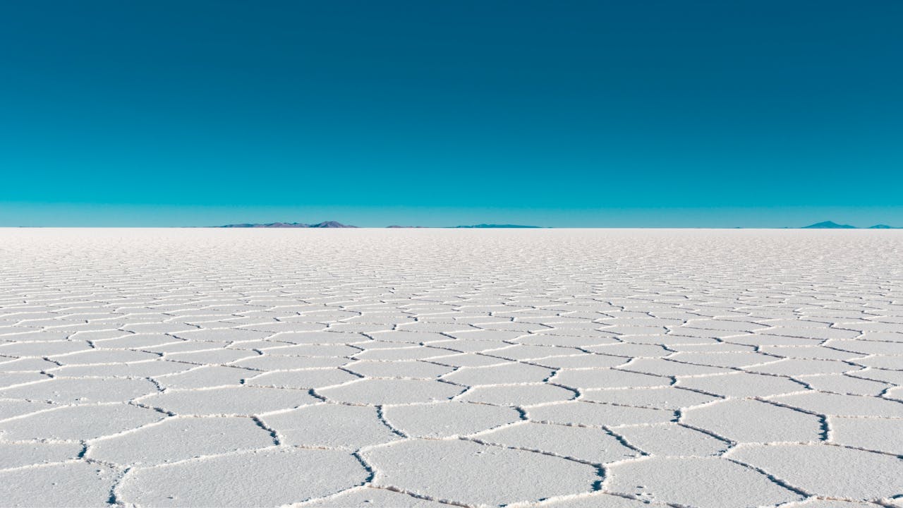 Vast salar with geometric patterns under a clear blue sky in Bolivias Uyuni.